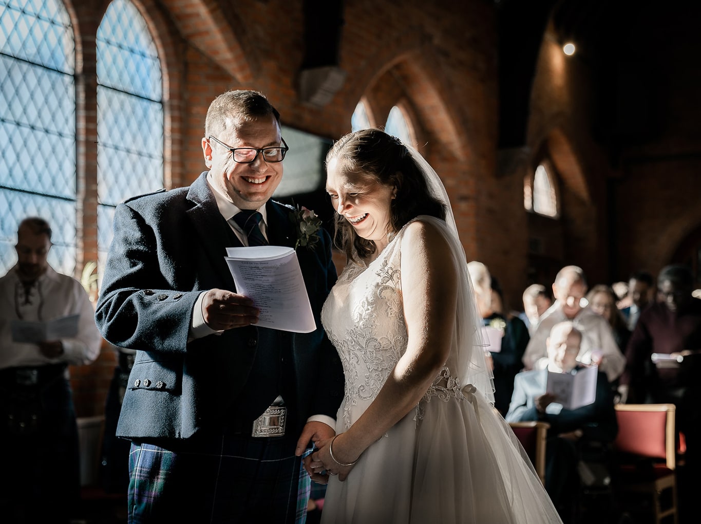 Bride and Groom holding hands and giggling during ceremony inside modern built church